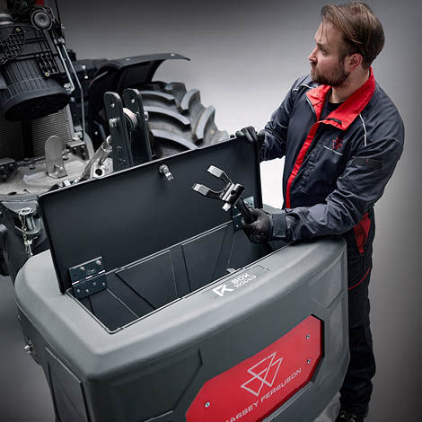 A technican in Massey Ferguson overalls opening a transport box on a tractor