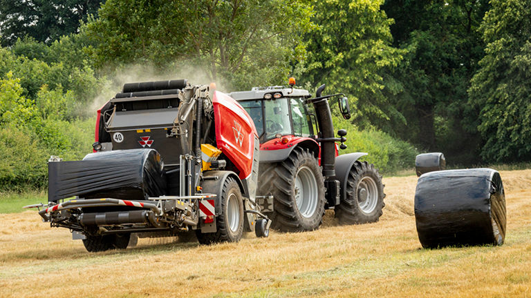 A picture of a Massey Ferguson baler working in a field with a bale of hay