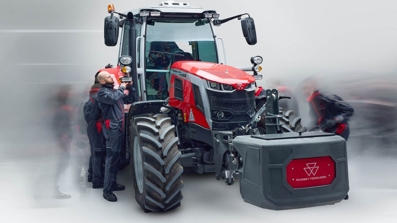 An image of a tractor with front weights and a technician standing by