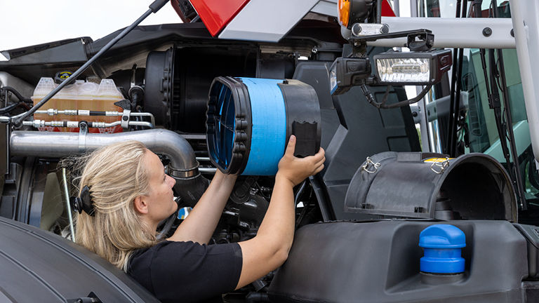 A female technician fitting a part to a tractor
