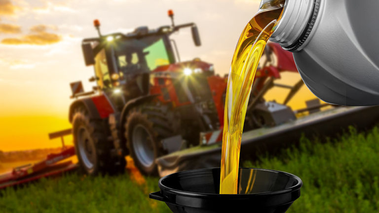 Lubricant being poured intoa  funnel with a Massey Ferguson tractor in the background