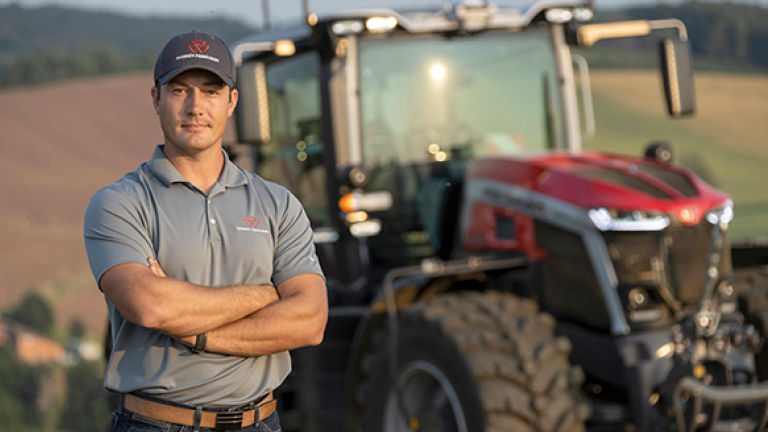 A technician standing arms folded in front of a tractor