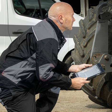 A technician holding a clipboard looking at a tractor