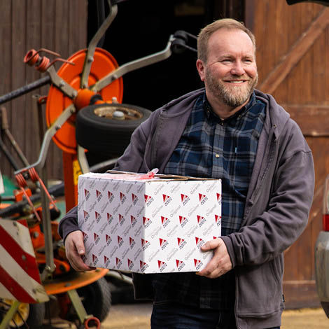 A smiling man holding an AGCO Parts box