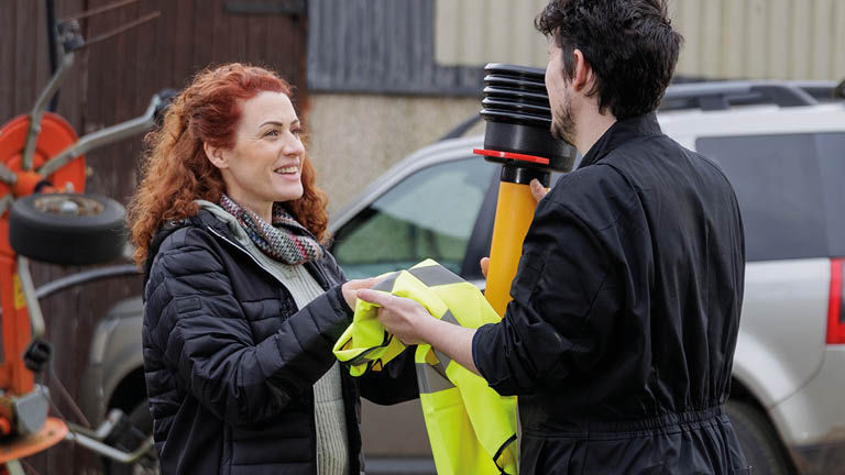 Woman handing hi vis vest to co worker