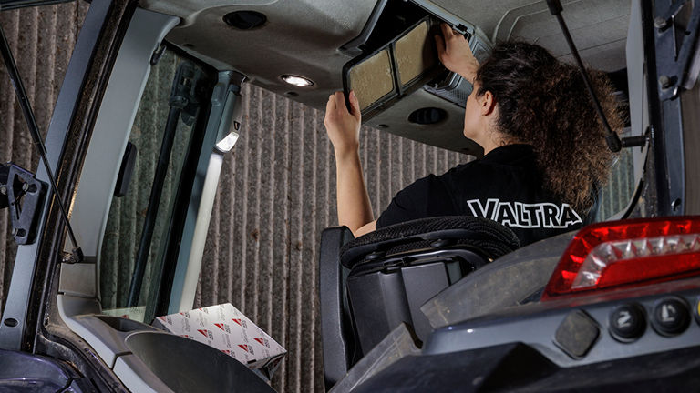 A technican examining a part inside a tractor cab