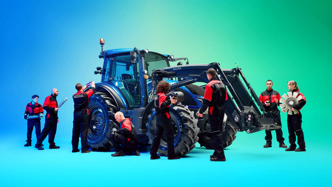 A group of Valtra technicans standing around a Valtra tractor