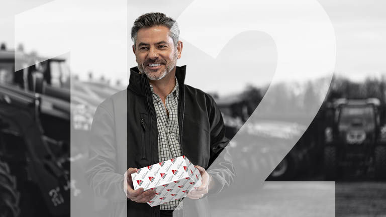 A man holding a box in front of some tractors with the number 12 superimposed