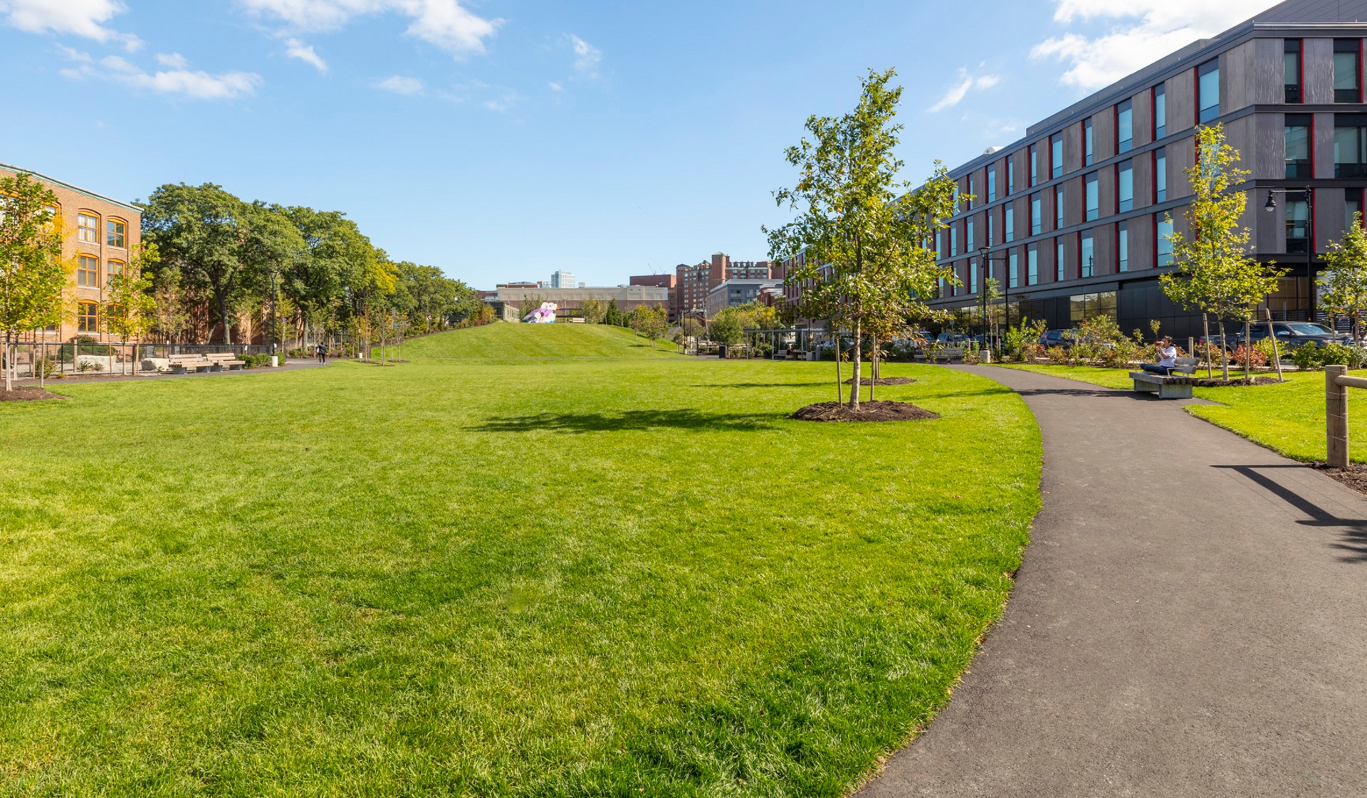 Axiom Apartment Homes - Cambridge, MA - Man sitting on park bench.Toomey Park, located one block down the street boasts an off-leash dog park, walking trails, event areas, playgrounds, and even a sledding hill.
