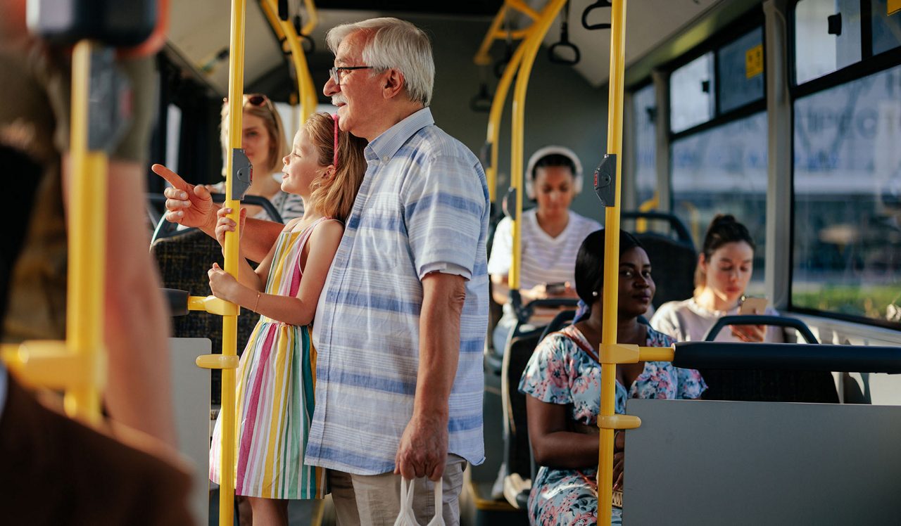 A senior man and his granddaughter are having a ride in the public transport