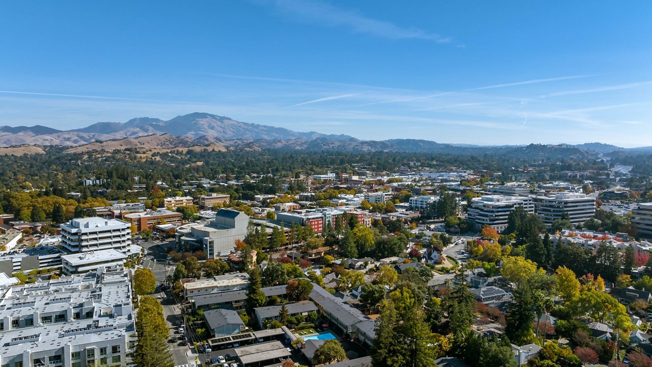 Aerial image over downtown Walnut Creek with businesses, houses and a blue sky 