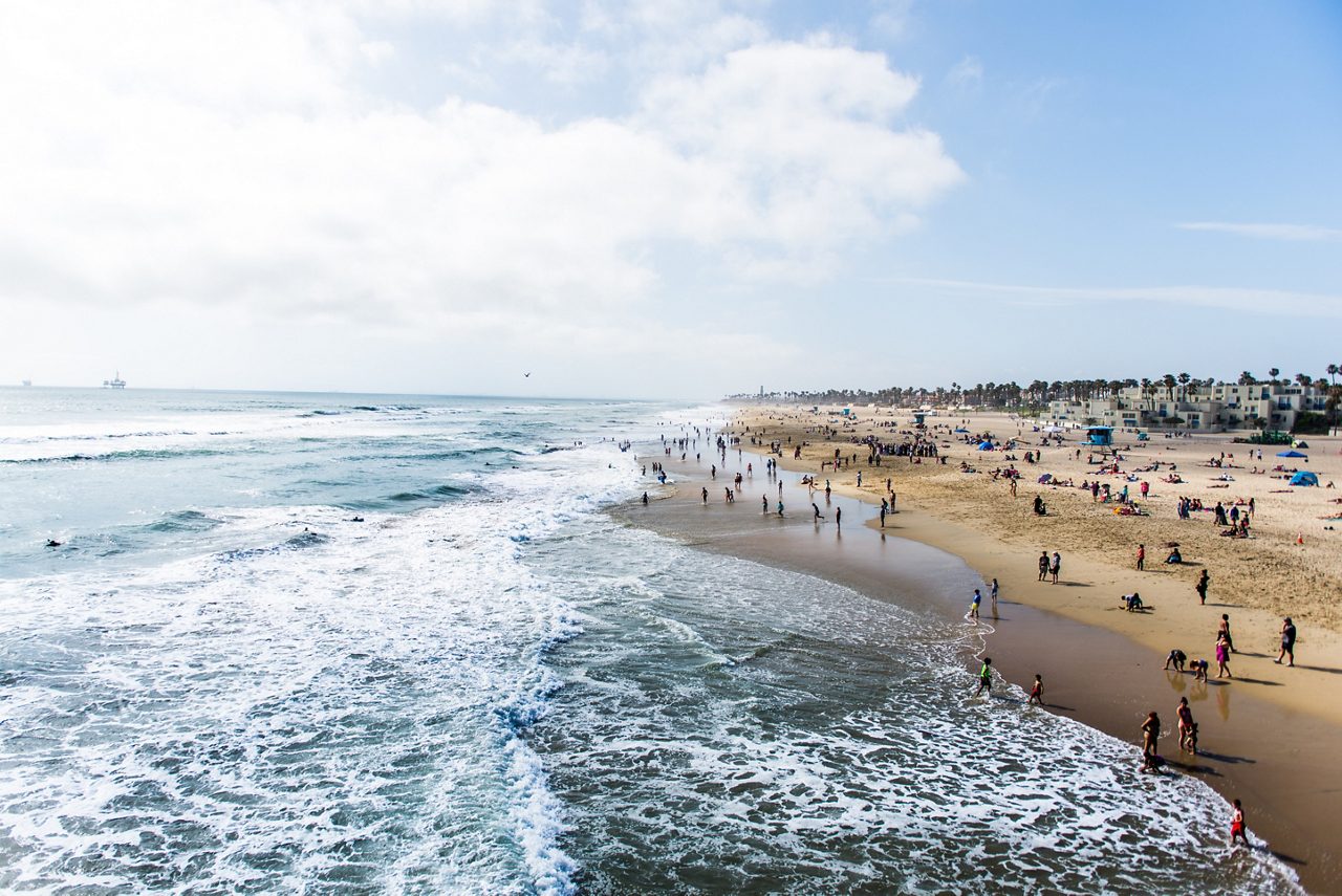 Crowds of tourists and sun bathers having fun and swimming at Huntington Beach.  California
