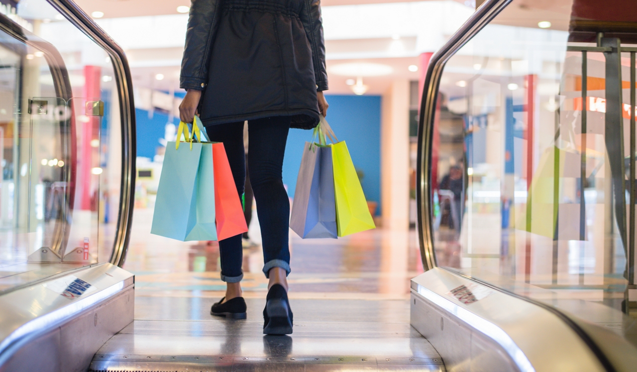 Laurel Crossing | San Matero, CA | Woman getting off escalator with shopping bags.<div style="text-align: center;">Convenient retailers and eateries are located at the Hillsdale Shopping Center, just a 5-minute drive away.&nbsp;</div>
