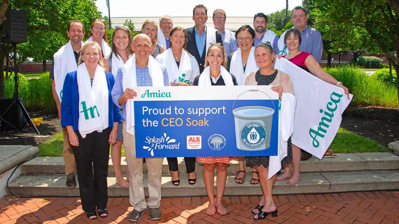 Group of wet business executives holding sign for ALS CEO Soak event.