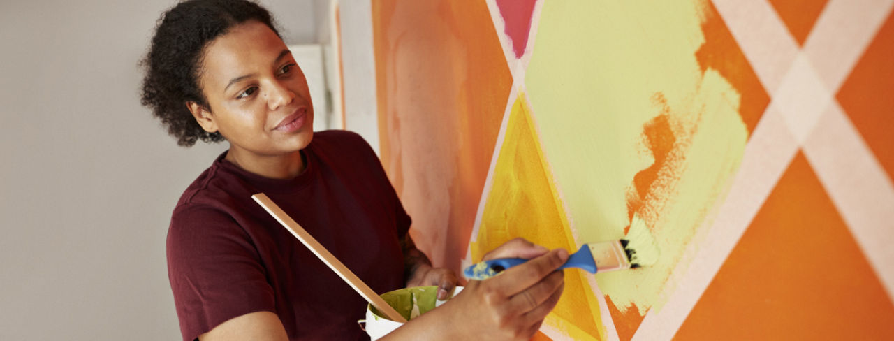 A woman painting colored walls in a playroom.