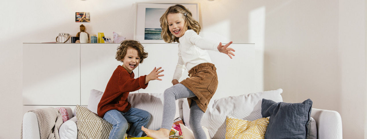 Two children playing on a couch.