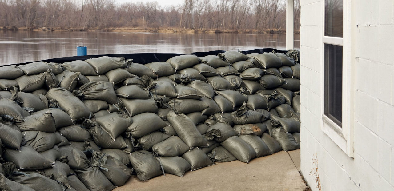 A house with sandbags piled high against floodwater.