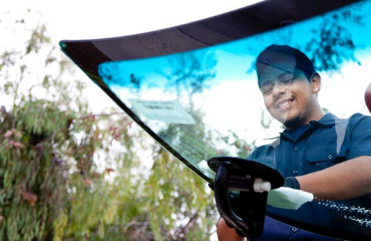 Glass technician in the process of placing a new windshield on to a car