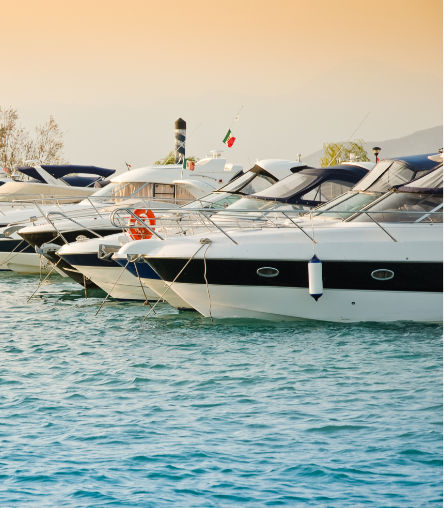 Multiple yachts anchored in line against late afternoon sky on rippling water 