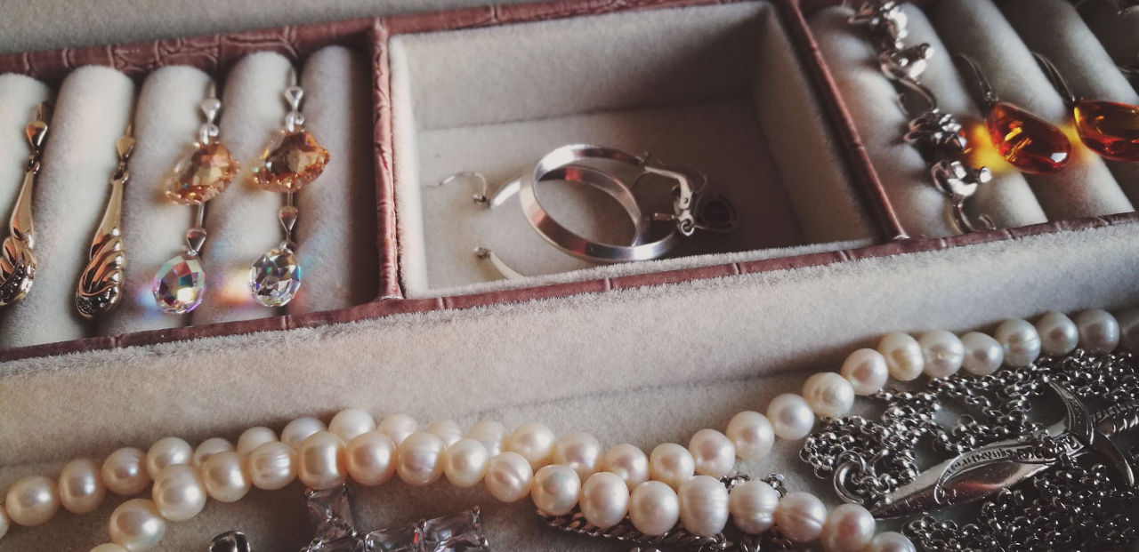 A jewelry box with earrings, rings and a pearl necklace.