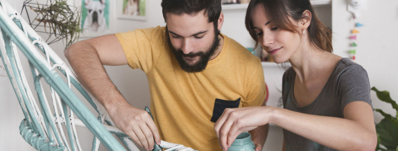 A man and a woman painting a chair.