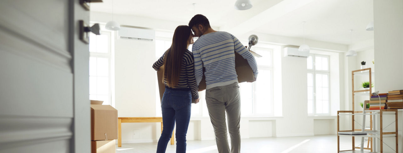 A couple standing in a new home with boxes.