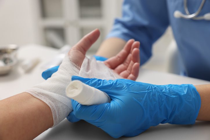 Nurse carefully wraps a patient's wound.