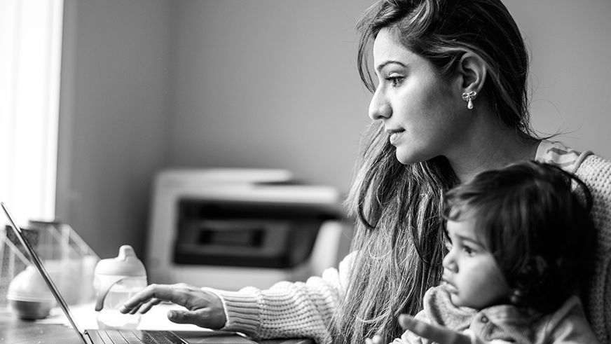 Mother multi-tasking with infant daughter in home office