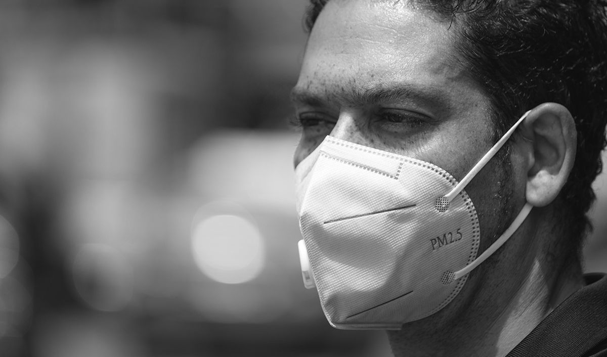Close up portrait of a man using pm 2.5 pollution mask in the street of a big city .