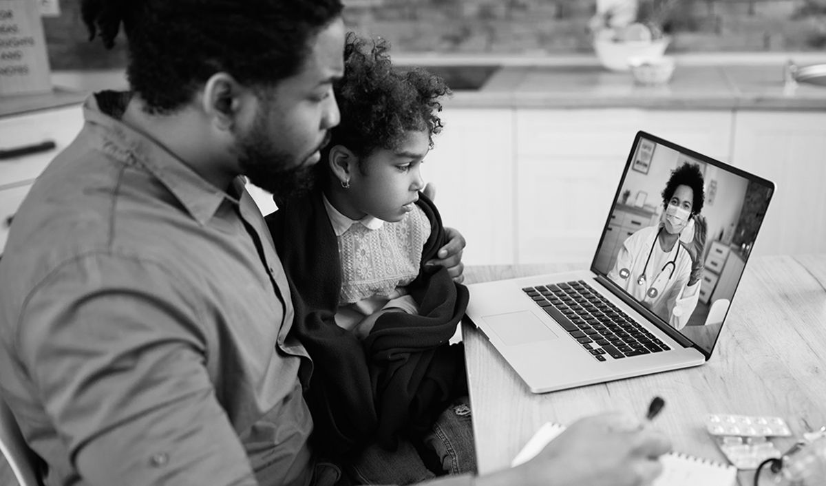 Man holding daughter while looking at laptop