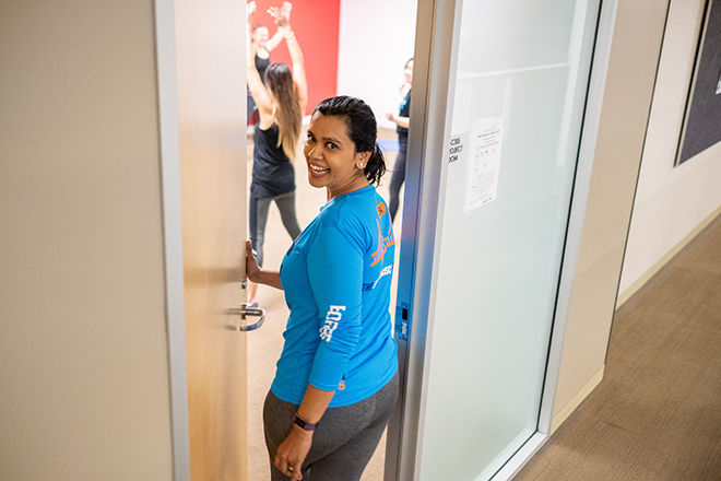 Smiling female opening door to excercise class