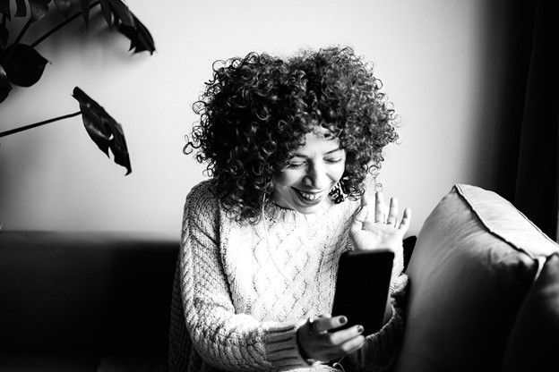 woman smiling and laughing at cell phone 