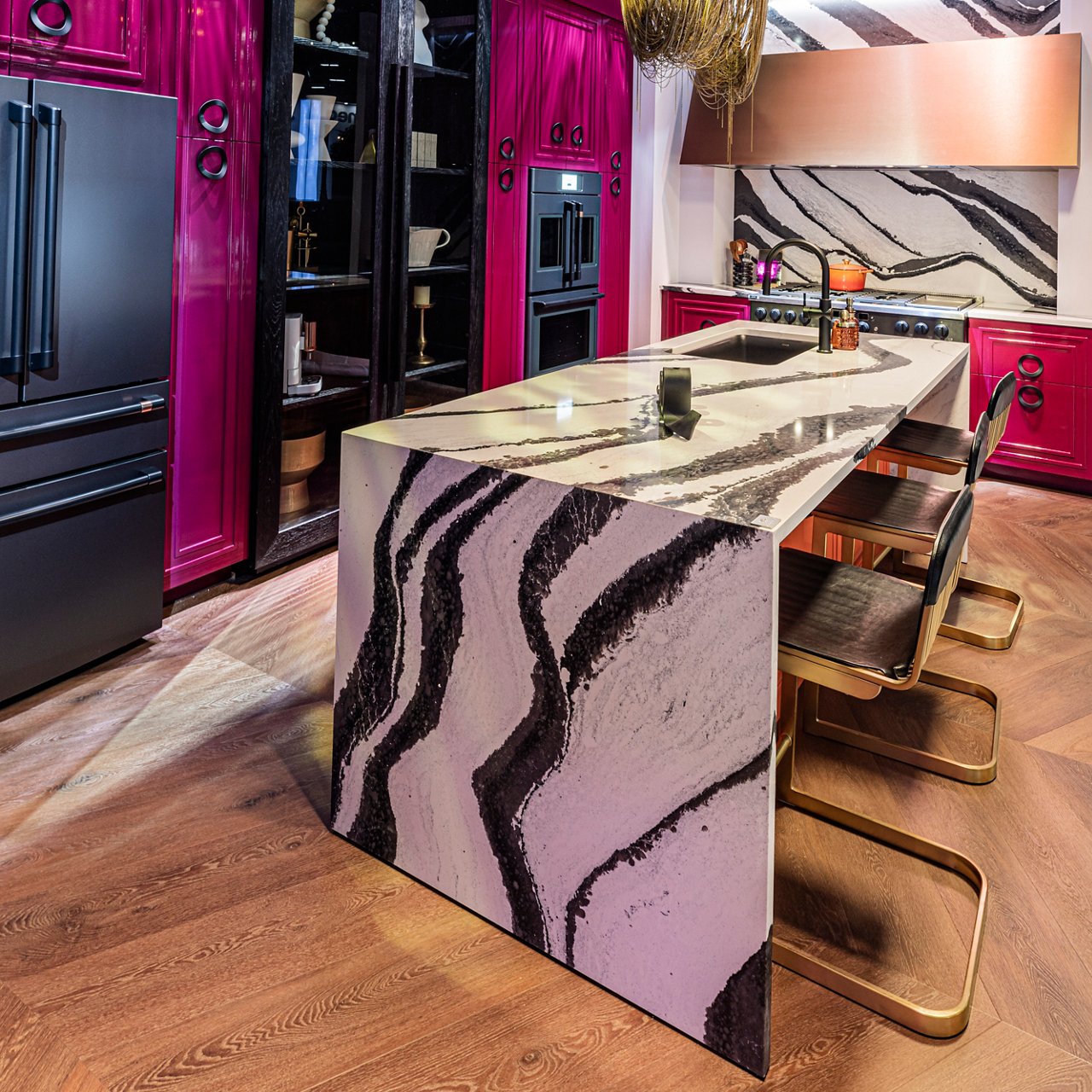 A kitchen with pink cabinets featuring an island with Cambria Bentley quartz countertops and siding.