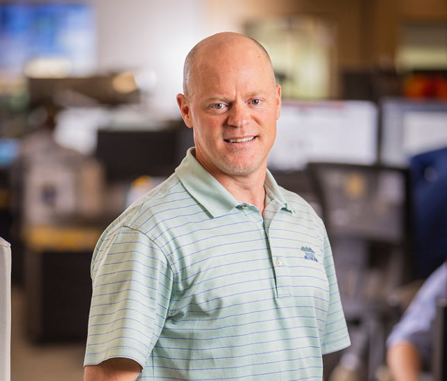 A portrait of a smiling man in an office.