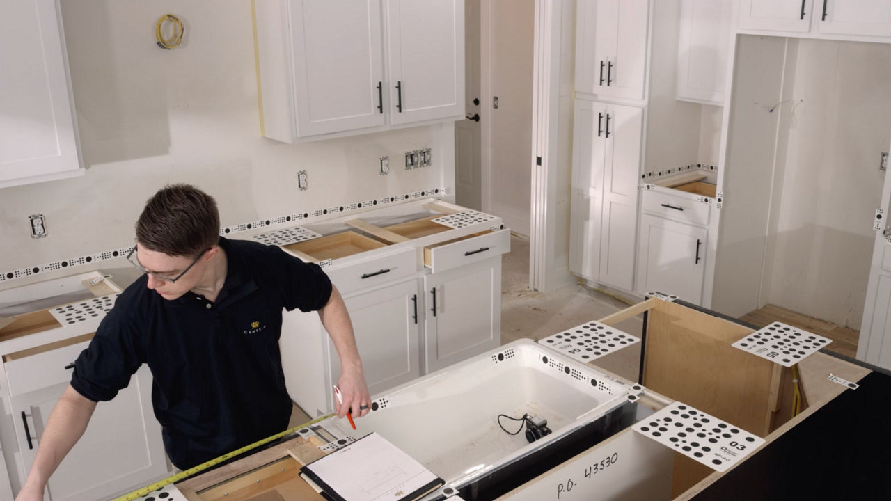 a Cambria employee measuring countertops for installation in a kitchen.