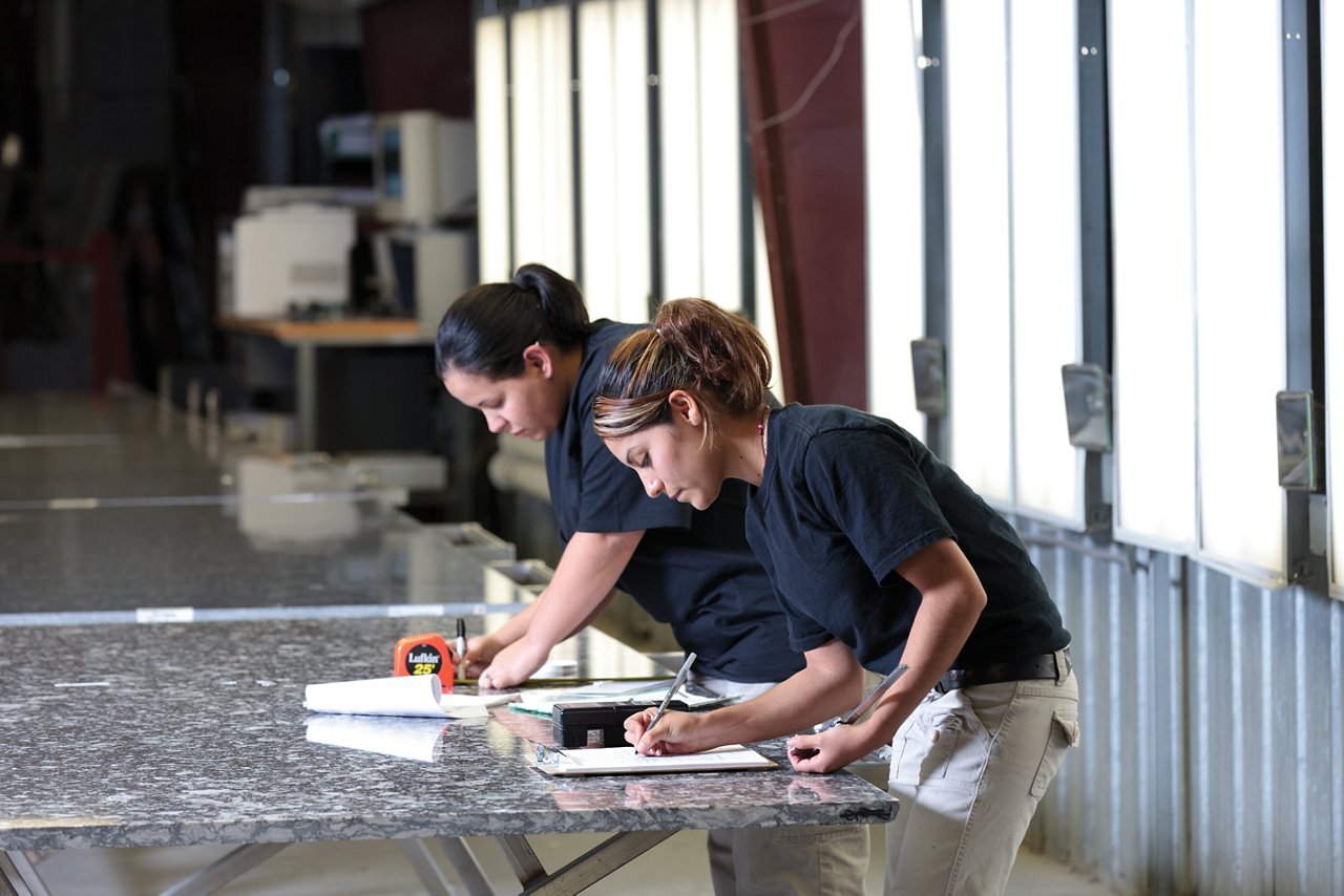 Two Cambria workers measuring and writing notes about a slab