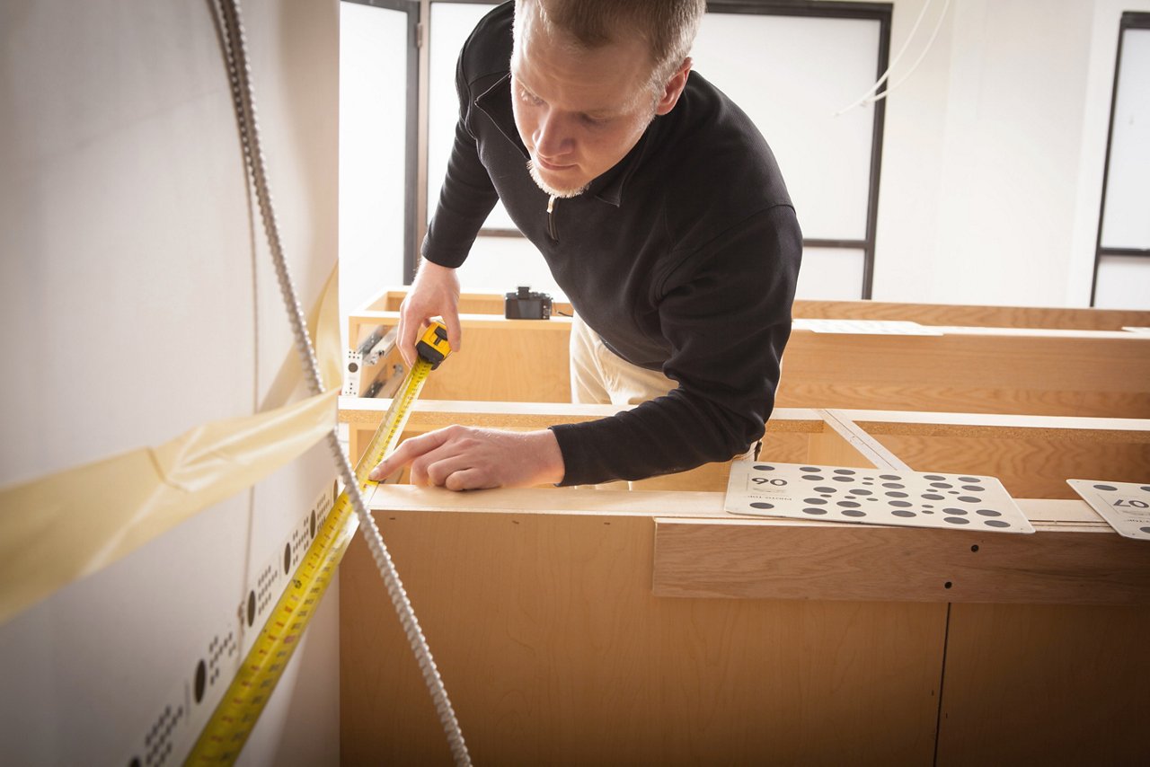 Cambria worker measuring a countertop for slab placement.