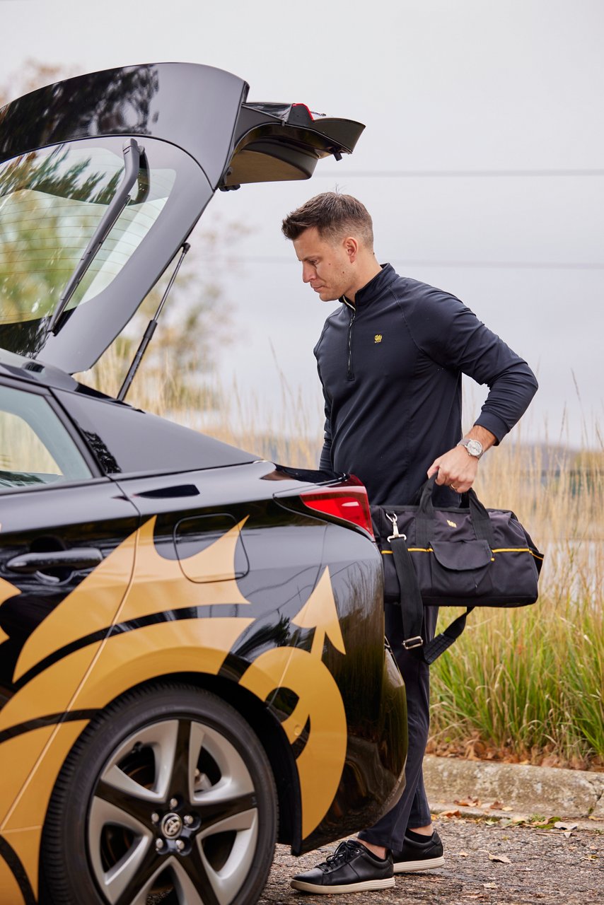 A man putting his bag in the trunk of the car.