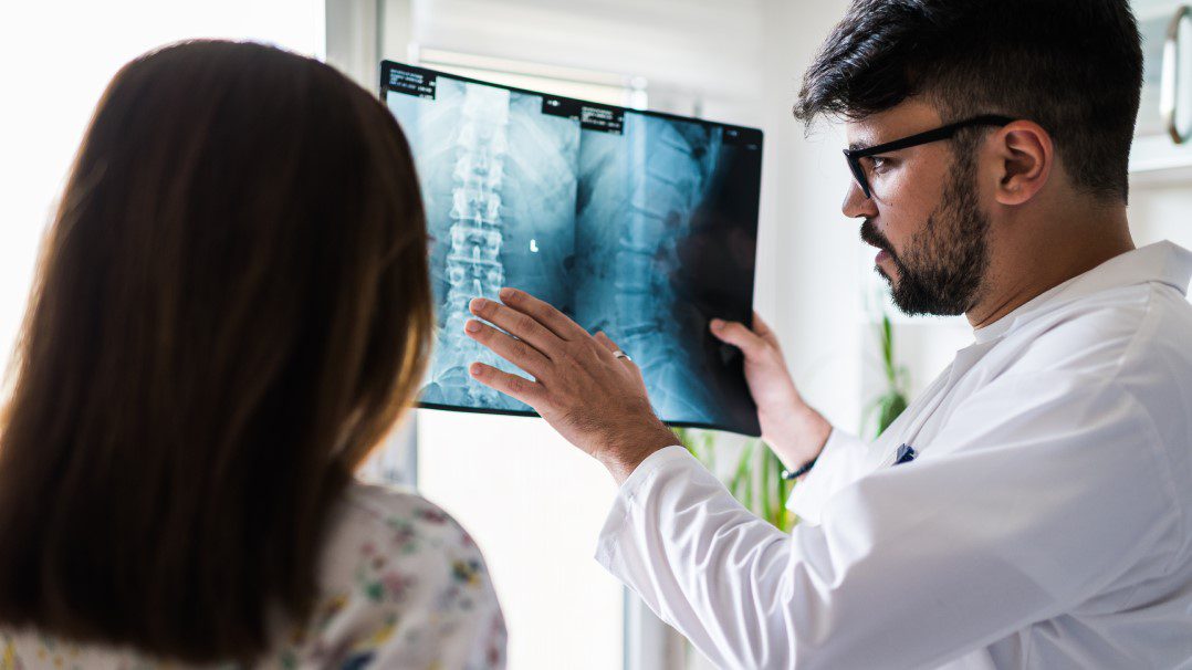 doctor with patient reviewing x-ray on lightbox