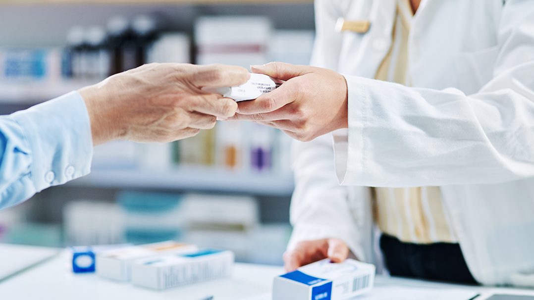 Pharmacist handing prescription to prescriber