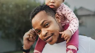 father carrying baby on shoulders