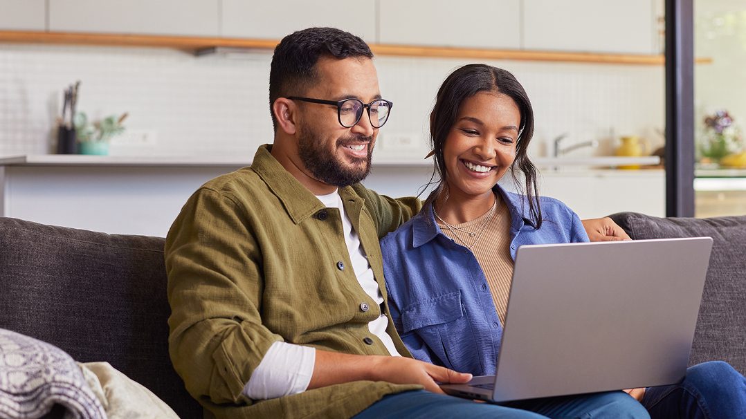 man and woman on couch looking at laptop
