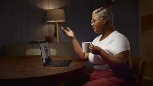 Woman holding a mug speaking to someone on a laptop