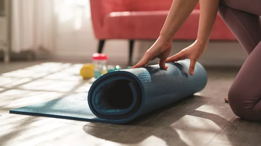 Cropped shot of  unrecognizable woman rolling up her yoga mat after class end.