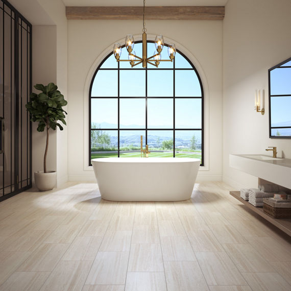 Bathroom with large arch window on backwall, white walls, beige stone look rectangle floor tile, white bathtub, and small tree in corner.