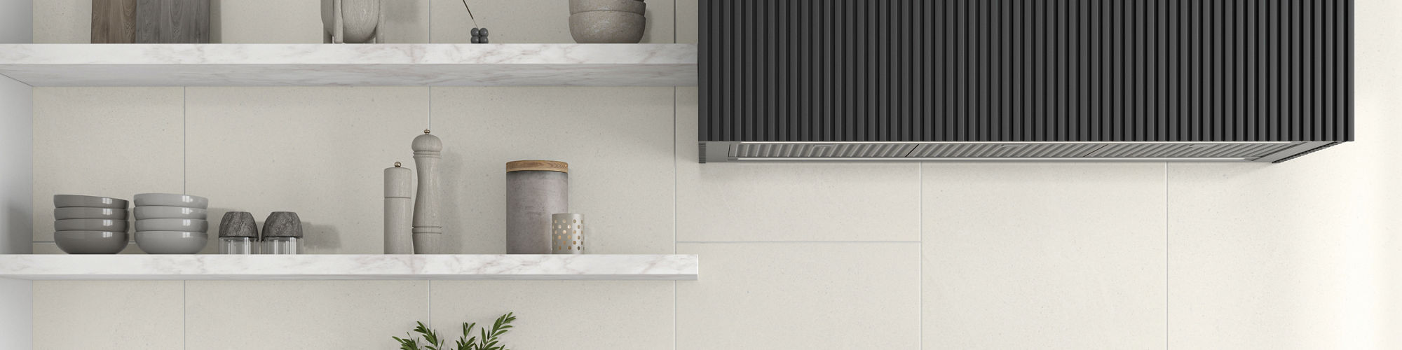 A contemporary kitchen features dark cabinetry with brass handles and a white marble countertop. A large ribbed dark range hood hangs above a built-in gas cooktop. Minimal open shelving displays dishes, bowls, cutting boards, and decorative bottles a