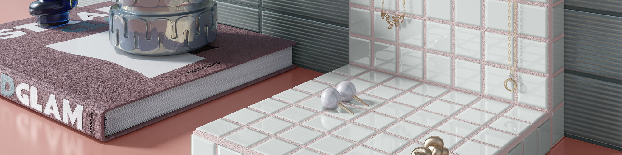 White square mosaic jewelry stand on a pink table, blue rectangle tile on back wall, and a book with a candle and plant on top.