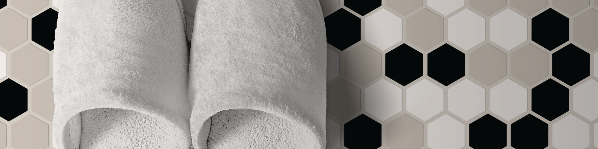 Two white slippers with a black, white, and light gray hexagon mosaic on the floor.
