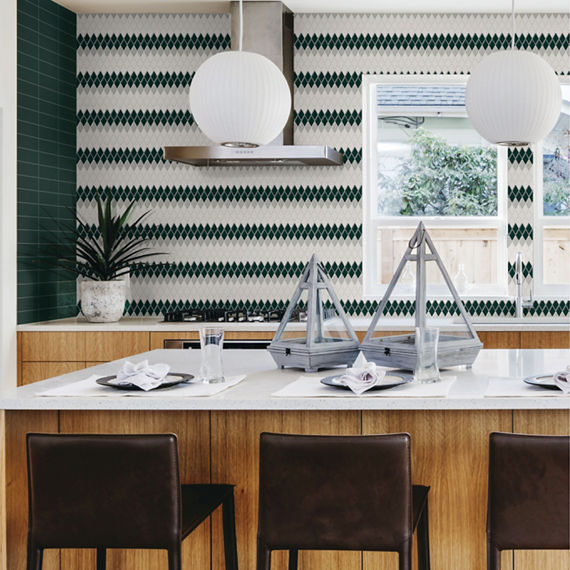 Kitchen with wood cabinets, center island, white countertop, and white and green harlequin mosaic on backsplash.
