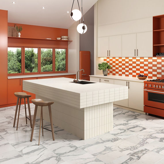 Kitchen with orange walls, white cabinets, white and orange subway tiles on backsplash, white tiles lining center island, and a marble look floor tile.